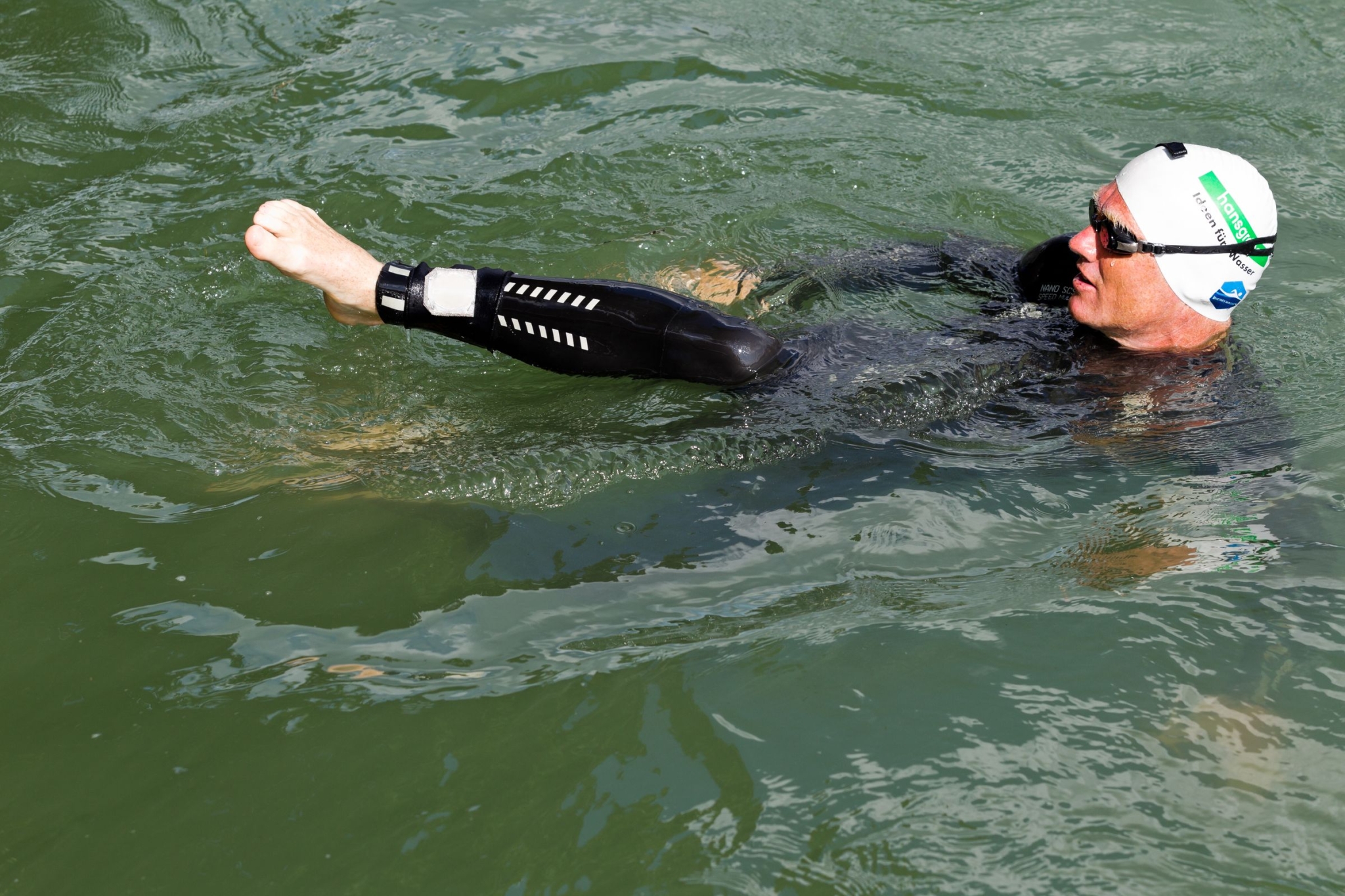 The photo shows a swimmer in the water wearng a neoprene suit and carrying a small bag at his leg.