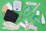 Various plastic medical items such as gloves, tablet blisters, containers, syringes and a blood pressure monitor are arranged on a green background.