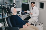 Laughing person with EEG on their head lying on a medical couch.